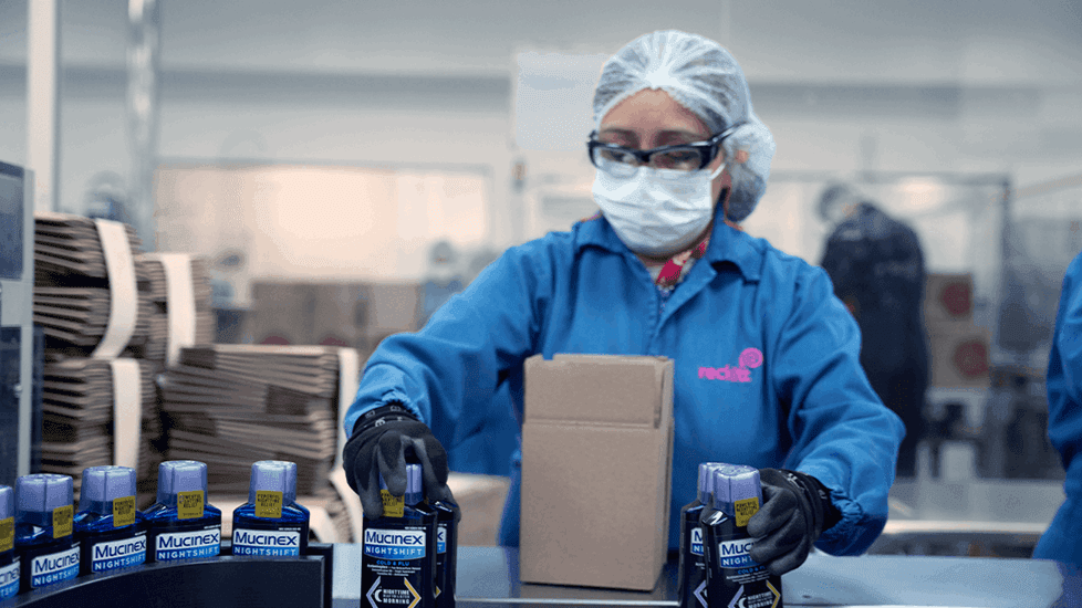 Woman working on a manufacturing line, packing Mucinex into boxes