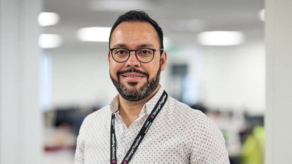 A Reckitt employee smiles at the camera, wearing a branded lanyard