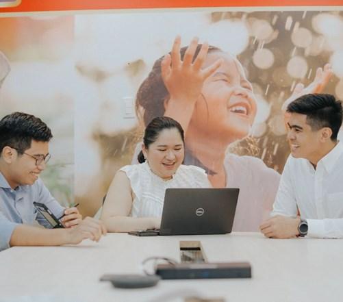 Three colleagues sitting around a laptop